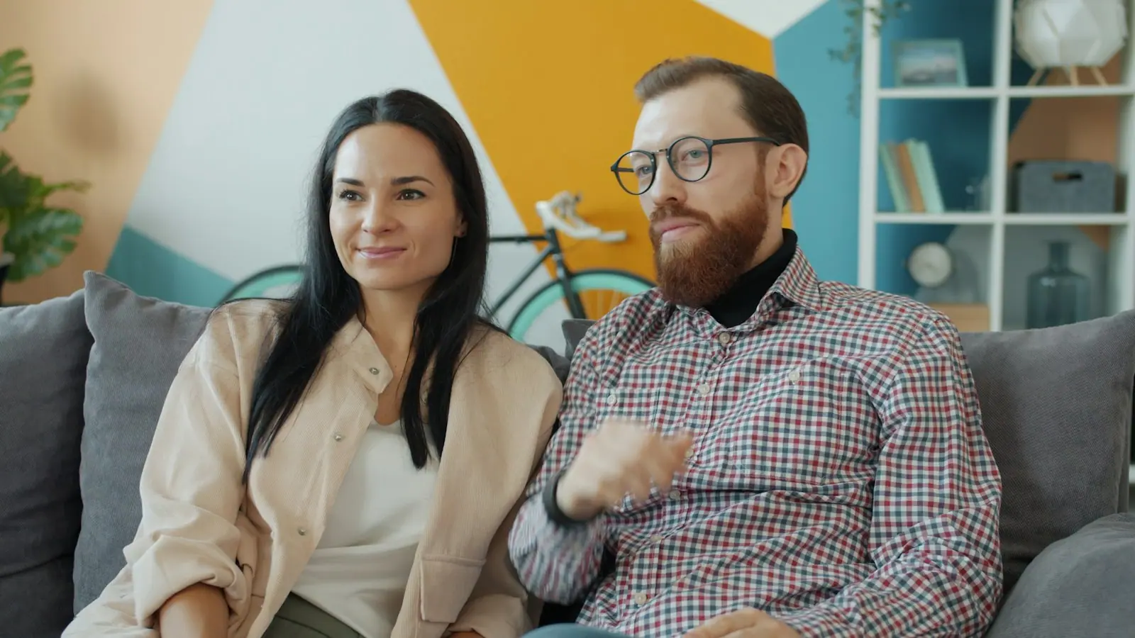 A couple sitting together on a sofa at home, smiling