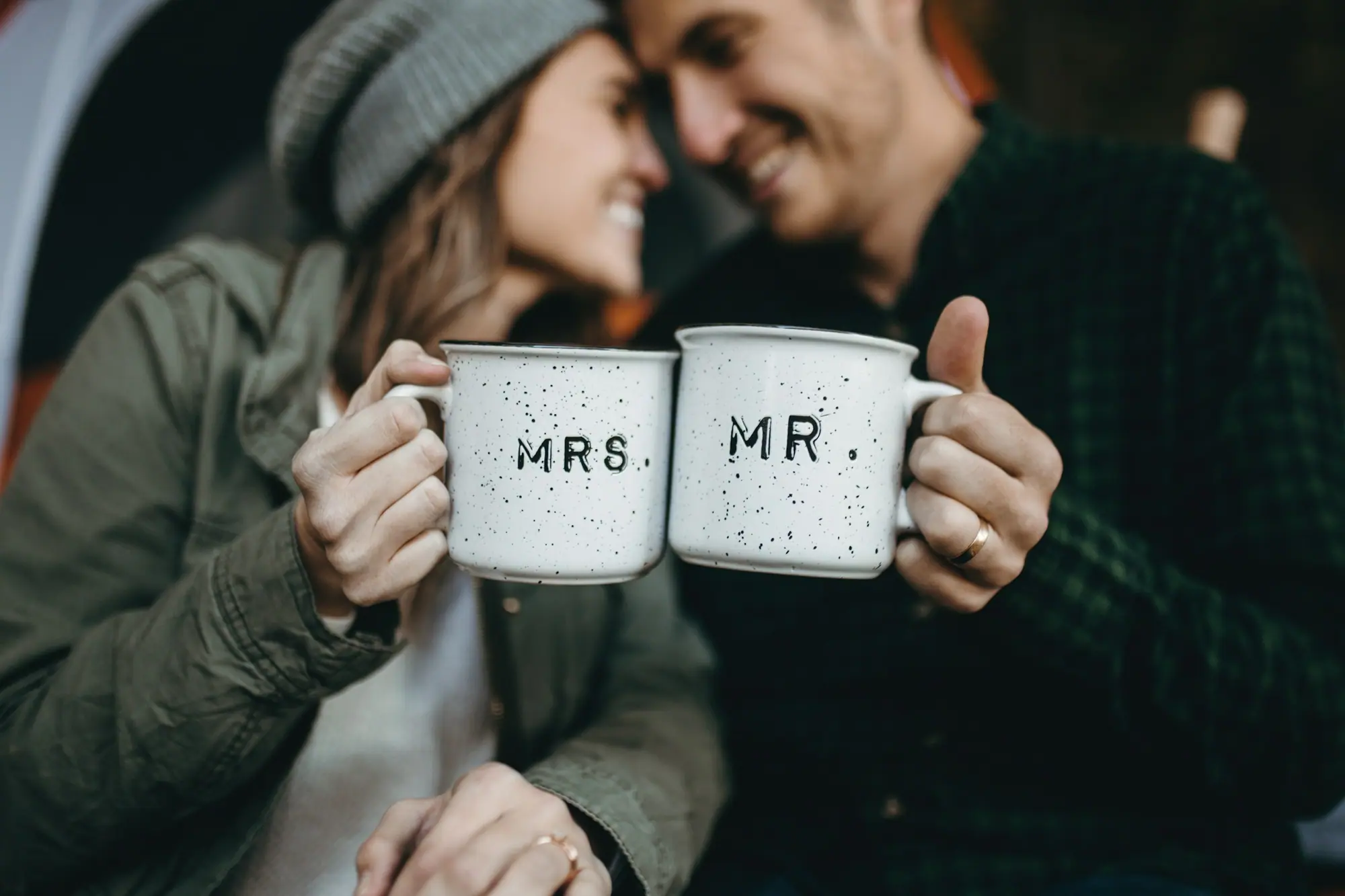 A smiling couple raising mugs marked Mrs and Mr