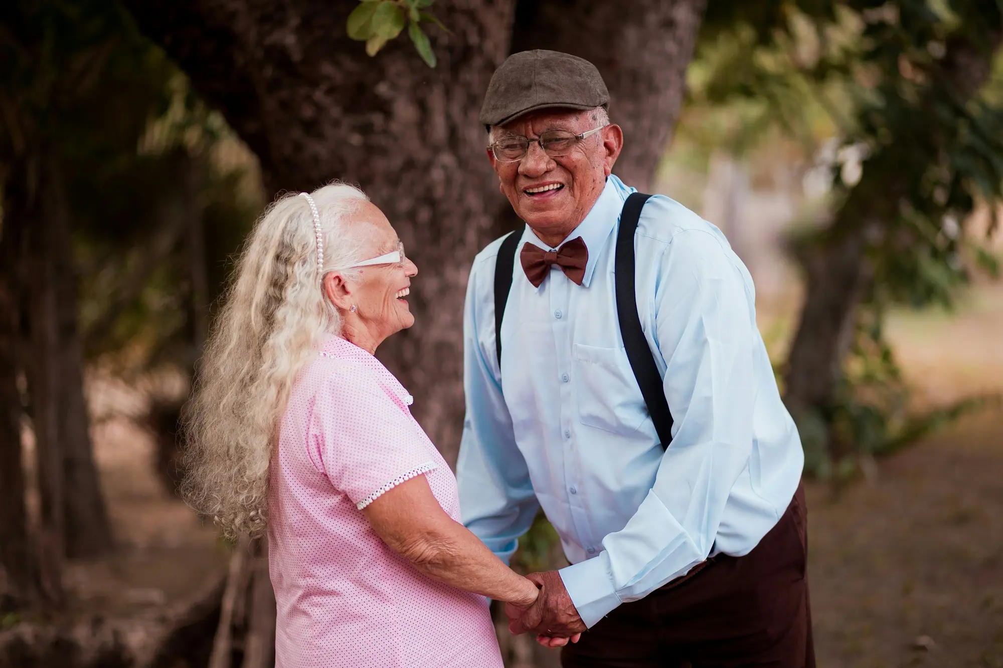 An older couple holding hands and smiling at each other outdoors