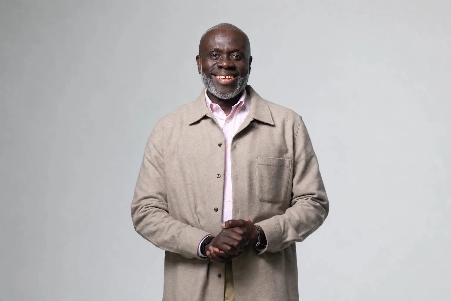 Pastor Victor K.A. Darteh smiling, in a light jacket with his hands clasped