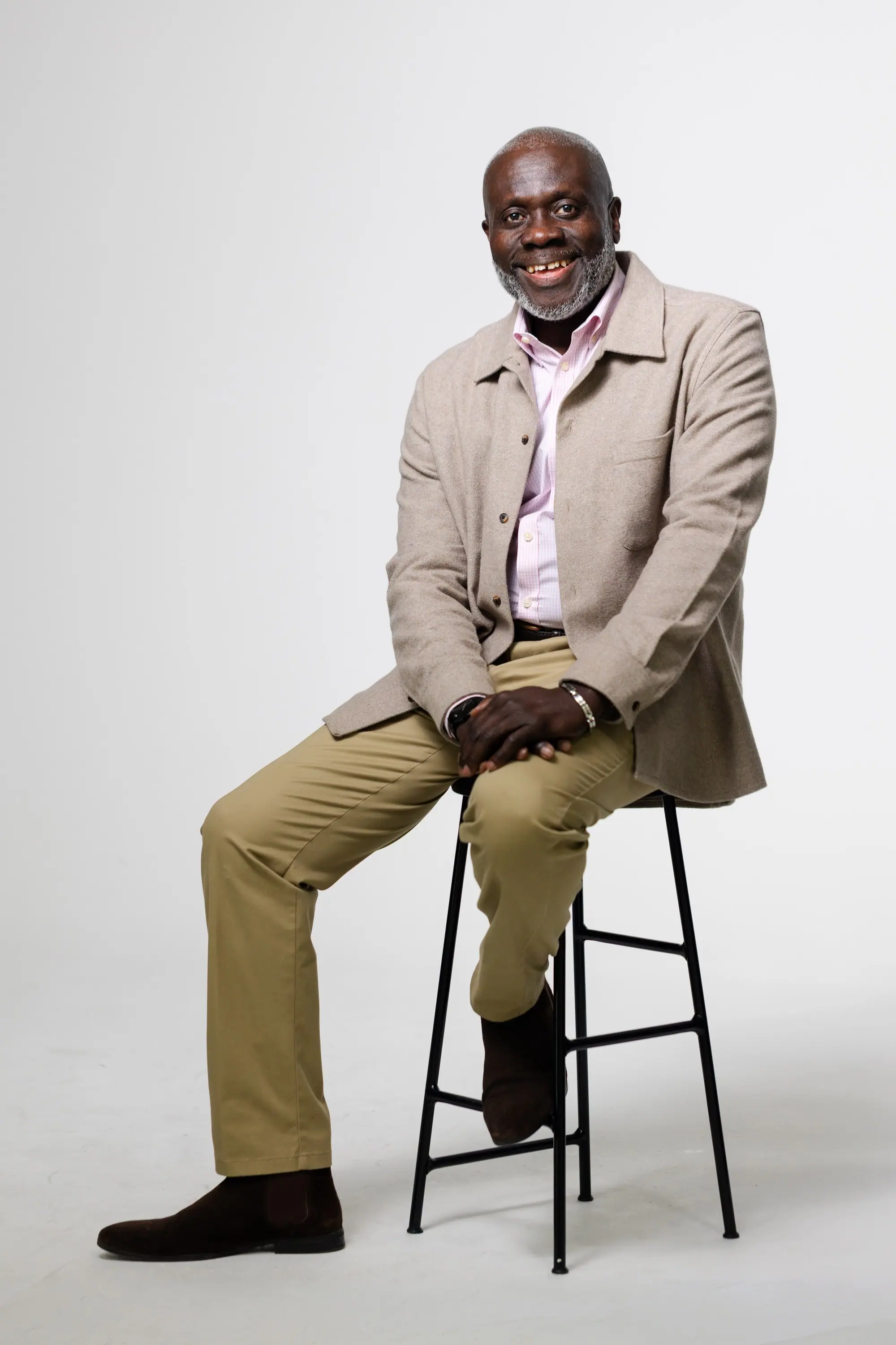 Pastor Victor seated on a tall stool, smiling